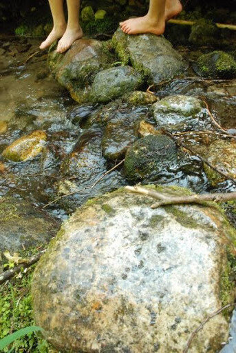 Photo by Claudia Ituarte-LimaChildren standing on rocks at the edge of a stream.